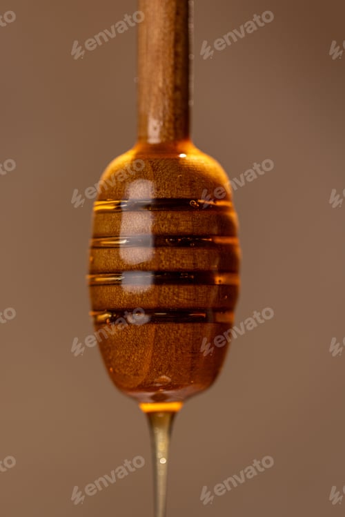 Preview: Fresh floral honey drips from a wooden spoon, close-up