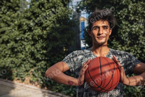 Preview: Young basketball player holding a ball on outdoor court