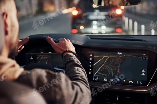 Preview: Rear view of handsome unshaved man in fashionable clothes that riding his automobile