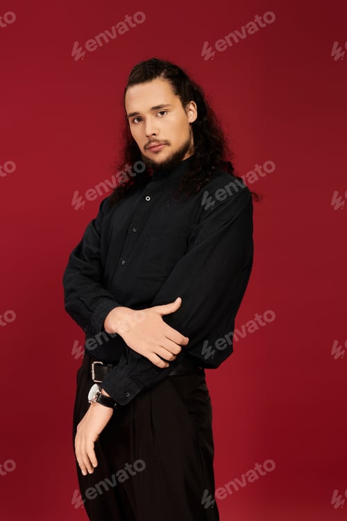Preview: Handsome young man with beard striking a confident pose against a vibrant red backdrop
