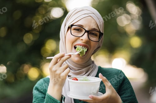 Preview: Close-up portrait of muslim business woman holding a vegetable salad in a plastic bowl
