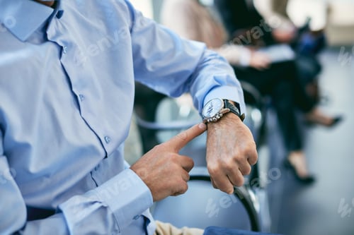 Preview: Close-up of businessman checking the time on his wristwatch in waiting room.
