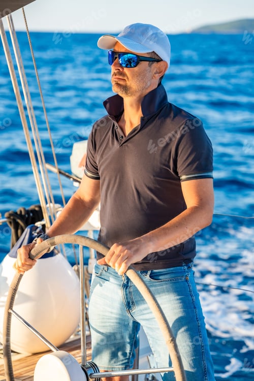 Preview: Young man captain stands at the helm and controls a sailboat during a journey by sea