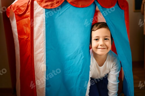 Preview: Happy little boy having fun in a tent while spending a day at kindergarten.