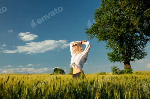 Preview: Beautiful blonde woman in wheat field in sunset time