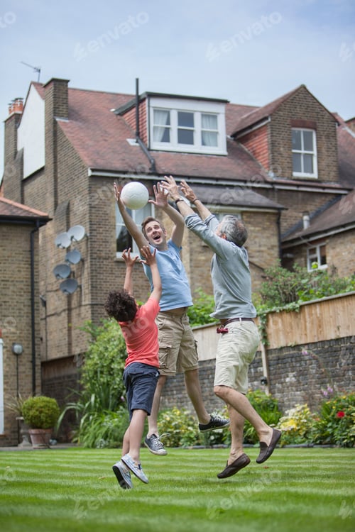 Preview: Three generation family playing with football in garden