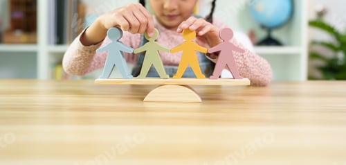 Preview: Unidentified little girl is trying to balance the people model on the wooden scale.