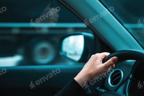 Preview: Getting away from it all concept, closeup of female hand on car steering wheel, woman driving