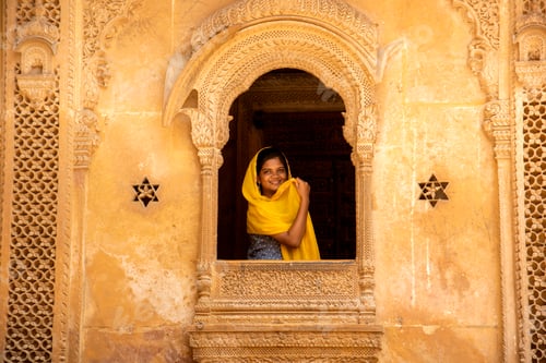 Preview: Young woman tourist in stone carved window, India.