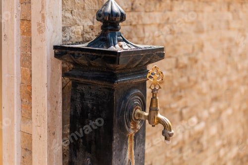Preview: A beautifully crafted brass water fountain stands against a stone wall