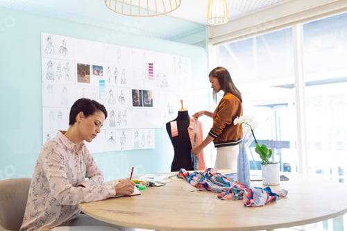 Preview: Attentive mixed race female fashion designers working in a modern office.