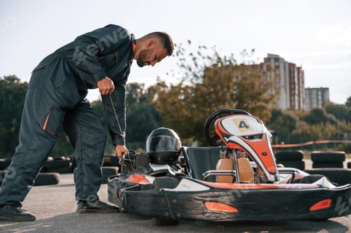 Preview: Mechanic Adjusting Go-Kart on Racetrack