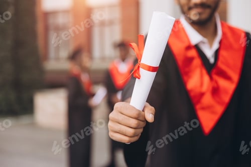 Preview: Young Graduate Holding Diploma During Outdoor University Graduation Ceremony