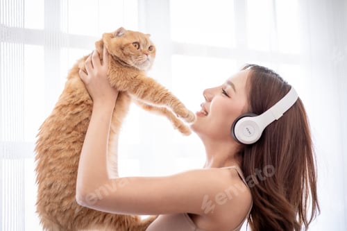 Preview: Asian beautiful woman holding her domestic cat with happiness at home.