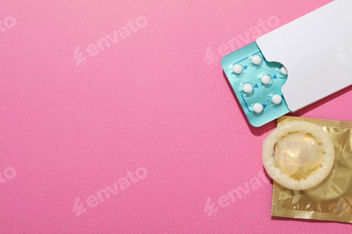 Preview: Condoms and birth control pills on a pink background, place for text