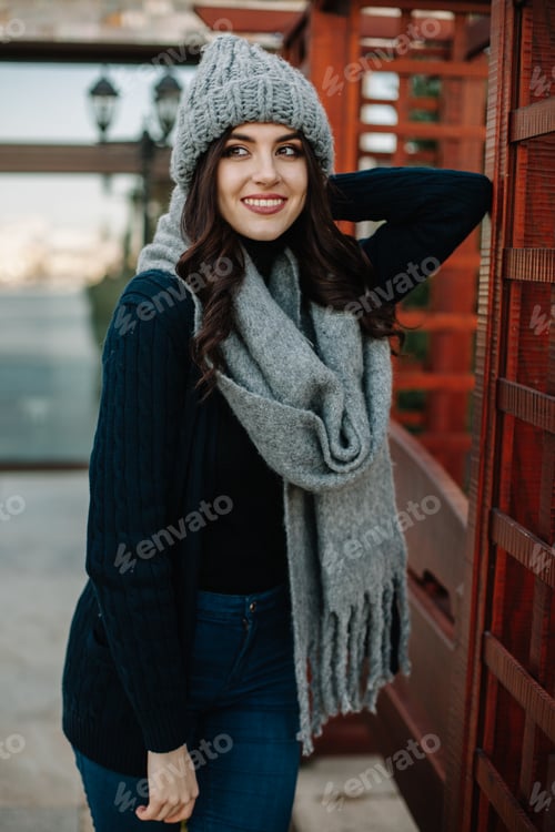 Preview: beautiful cheerful girl posing in blue knitted hat and scarf, isolated on grey
