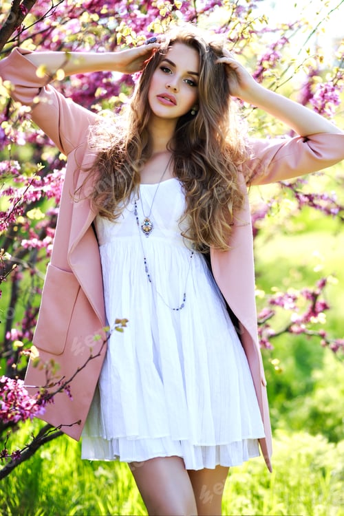 Preview: Attractive pretty young woman in walking in garden of spring time.