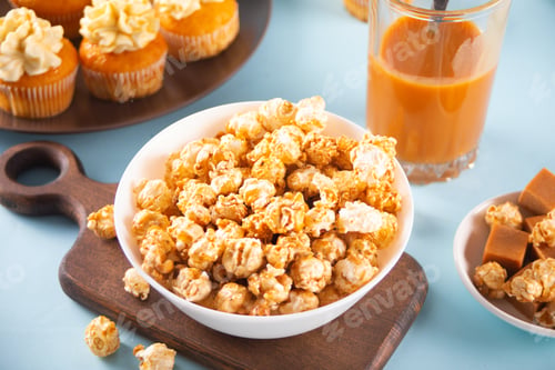 Preview: Caramel popcorn snack on white bowl with delicious cupcakes and caramel syrup in jar