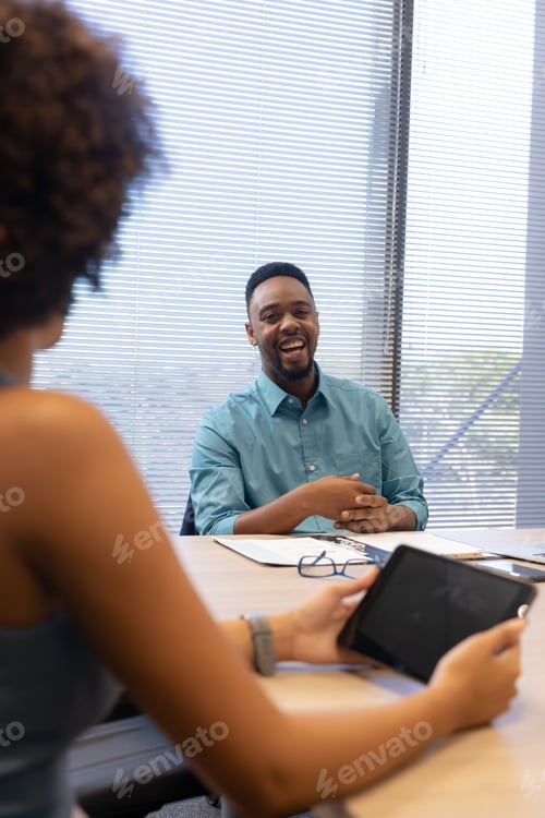 Preview: Happy african american businessman planning strategy with hispanic businesswoman in boardroom