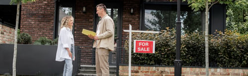 Preview: positive realtor talking to client near house, plants and for sale signboard on street, banner