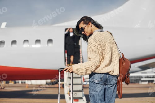 Preview: At daytime. Young female passanger in casual clothes is outdoors near the plane