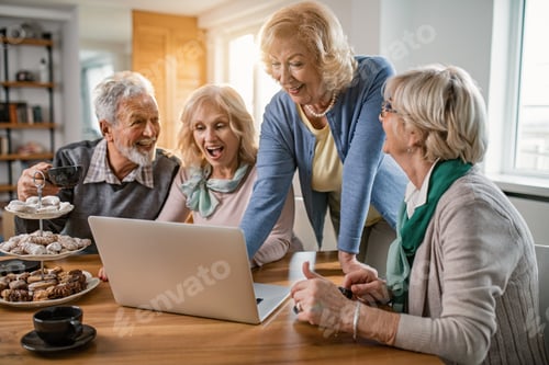 Preview: Cheerful seniors having fun while using laptop at home.