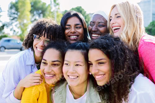 Preview: Happy group of diverse women friends hugging each other posing for photo outdoor