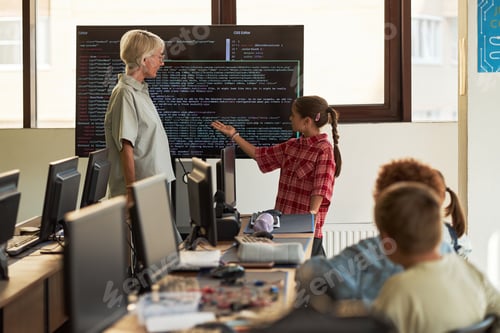 Preview: Senior Woman Observing Girl Child Presenting Programming Code in Classroom