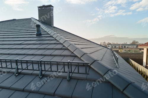 Preview: Closeup snow guard for safety in winter on house roof top covered with ceramic shingles.