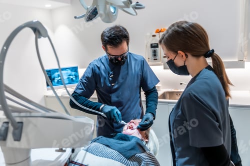 Preview: Dentist performing dental procedure on senior patient with assistant