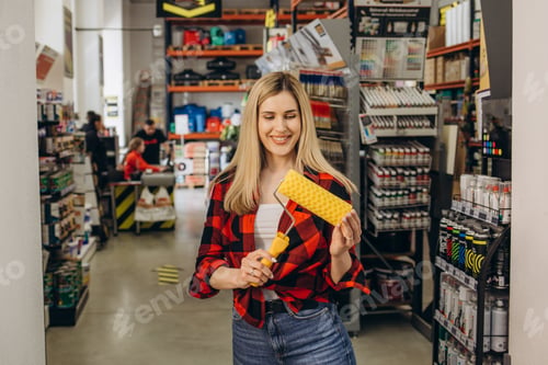 Preview: Adult girl is purchasing tools for house improvements in paint supplies store.