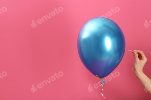 Preview: Woman piercing balloon with needle on color background, closeup. Space for text