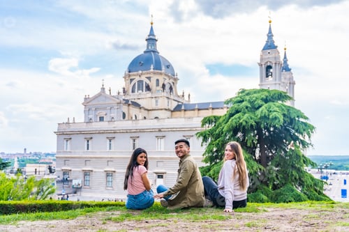 Preview: Portrait of tourist friends visiting Madrid city on summer vacation. Sitting looking at the Almudena