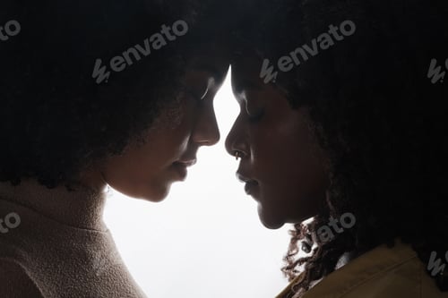 Preview: Cropped shot of a beautiful young female couple posing in studio against a dark background
