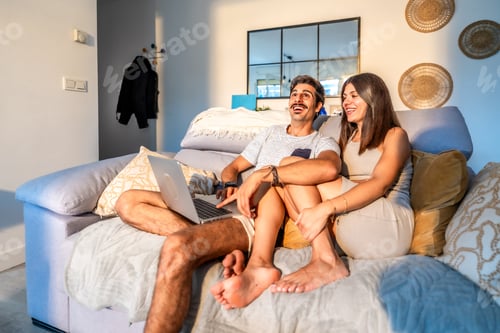 Preview: Happy couple watching streaming movie on laptop in living room