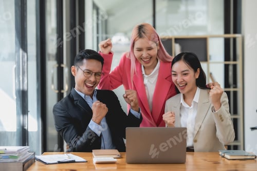 Preview: Three ecstatic asian business professionals celebrating a victory with a fist pump