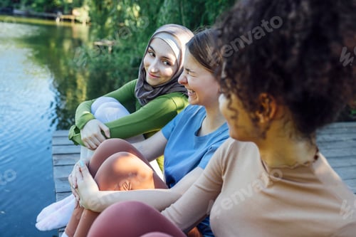 Preview: Multiracial young teen female friends resting in the park after sport training laughing