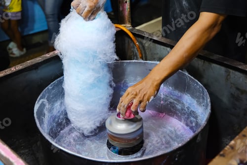 Preview: Man making blue cotton candy at street food stall.