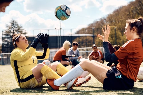 Preview: Soccer goalie and her teammate doing sit-ups while passing ball to each other on sports training.