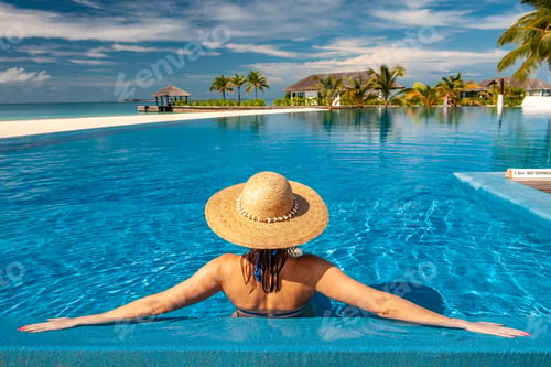 Preview: Woman with hat at beach pool in Maldives