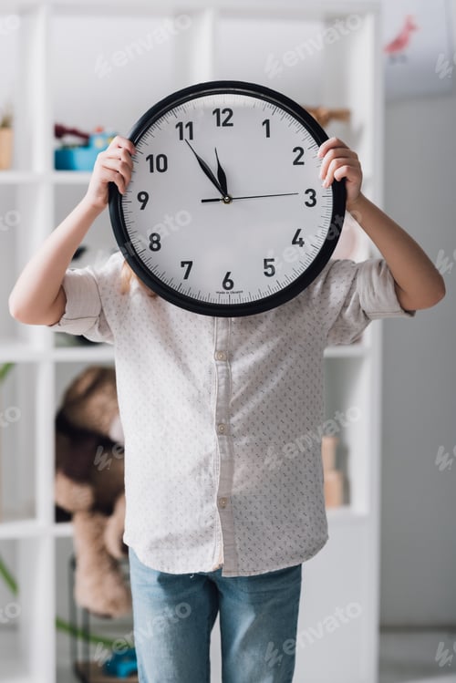 Preview: little child covering face with big clock