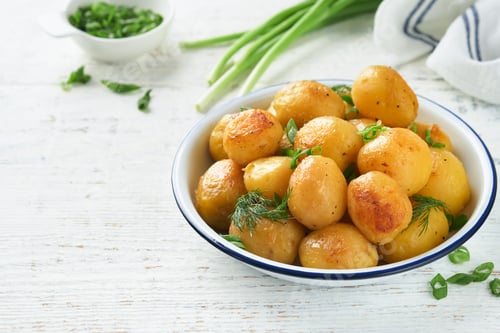 Preview: Boiled new or young potatoes with butter, fresh dill and onions in white bowl on white old rustic wo