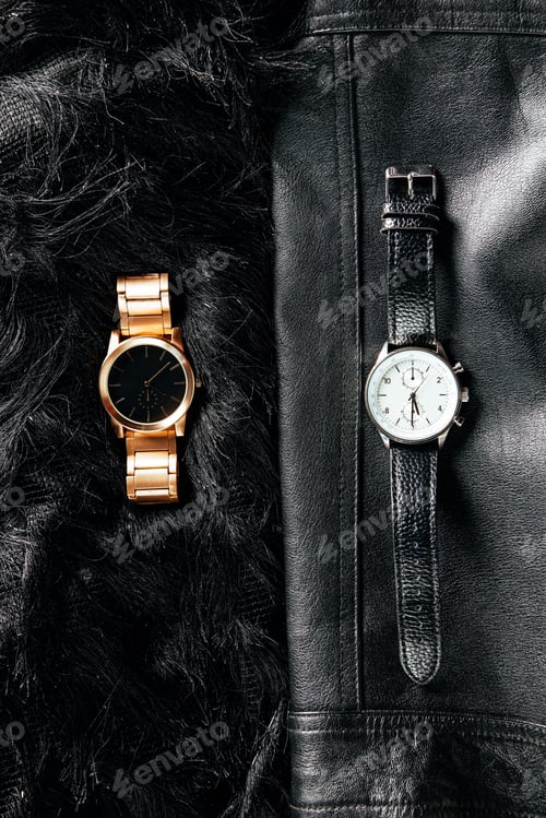 Preview: top view of luxury masculine and feminine wrist watches on black leather and woolen background