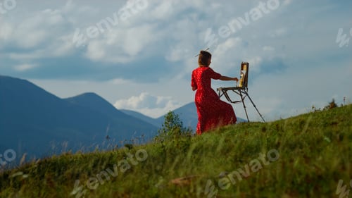 Preview: Unknown woman artist drawing outdoors. Lady painter painting in mountains.