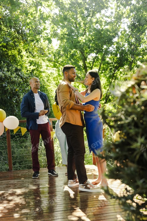 Preview: Dancing outdoors, African American couple at party with friends and balloons
