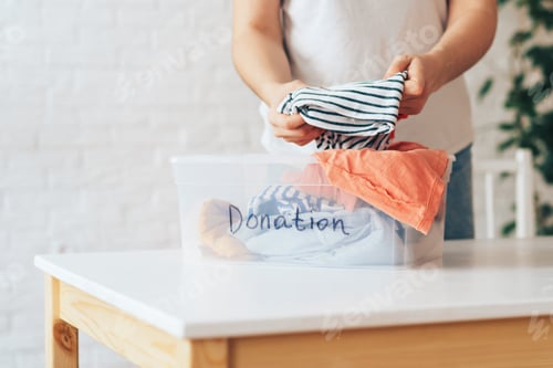 Preview: Girl puts used clothes in plastic container with the inscription donation