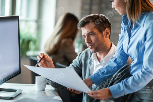 Preview: Businessman and his female colleague working on reports in the office.