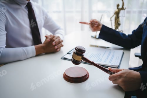 Preview: Lawyer holding a gavel and explaining a contract to her client during a meeting