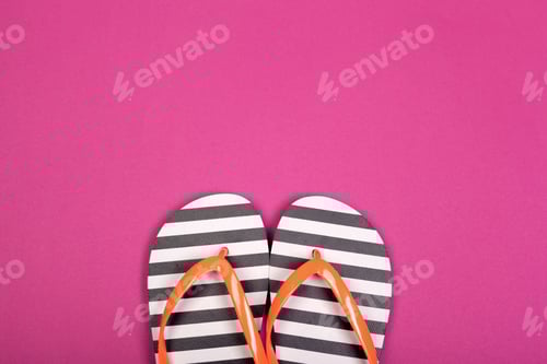 Preview: Flip flops on a bright pink background ready for summer fun at the beach or poolside