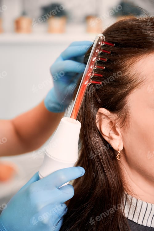 Preview: Hair specialist brushing woman hair with laser comb.